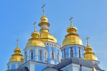 Fototapeta na wymiar Eastern orthodox crosses on gold domes (cupolas) with a blue sky