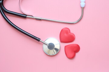 Stethoscope with red heart on pink background with copy space