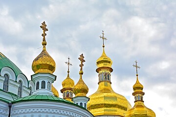 Fototapeta na wymiar Eastern orthodox crosses on gold domes (cupolas) against grey cloudy sky