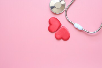 Stethoscope with red heart on pink background with copy space