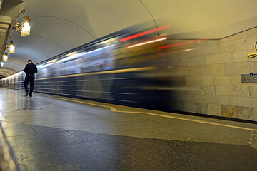 Blurred departing subway (underground) train, seen from the back, with a passenger walking away
