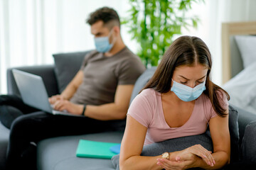 Couple man and woman work and sit on sofa in living room and they stay far from each other to concept of social distancing during covid virus spread or pandemic in city and they try to prevention.