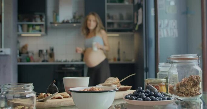 Healthy eating, cooking, pregnancy and people concept. Pregnant woman preparing healthy yummy snack breakfast with fruits and at home kitchen.