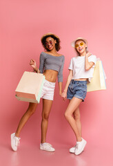 Summer Shopping. Multiethnic Girlfriends Posing With Colorful Shopper Bags Over Pink Background