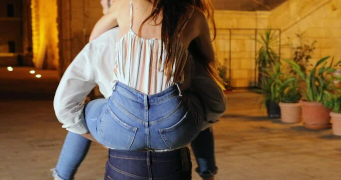 MS TS Four young people having fun with piggyback ride on street at night / Cagliari, Italy