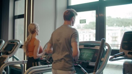 Fit couple running on treadmill at gym. Sporty family doing cardio in sport club