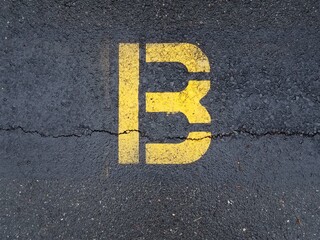 cracked black asphalt with yellow letter B
