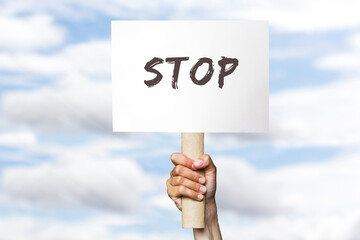 activist with a stop poster. protest banner on cloudy sky background