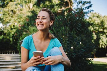  pretty female is reading text message on her cell telephone while relaxing in the park