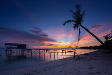 Amazing beautiful sunset with silhouette wooden jetty and coconut tree