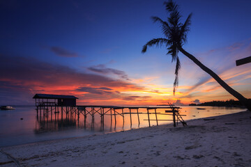 Amazing beautiful sunset with silhouette wooden jetty and coconut tree