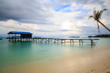 Beautiful scenery landscape view of long wooden jetty and white sand beach with blue sky ocean and green ocean