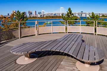 Japan. A place to relax with a view of Tokyo Bay. Rainbow bridge in Tokyo. Autumn panorama of the capital of Japan. The Island Of Odaiba. A bench of unusual shape on the shore of Tokyo Bay.