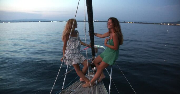 Two young women enjoying trip on a sailboat in the Ligurian Sea.