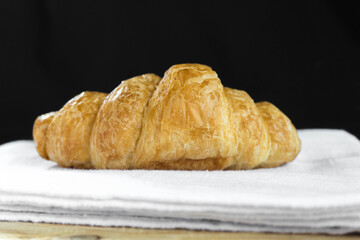 Fresh croissant on white fabric with wooden table and black background