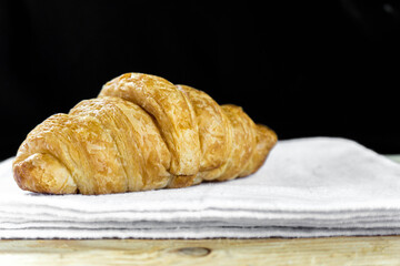 Fresh croissant on white fabric with wooden table and black background