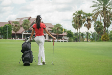 Obraz premium Young woman holding a golf club and looking away while standing on golf course.
