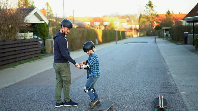 father and son skateboarding on a suburban street.