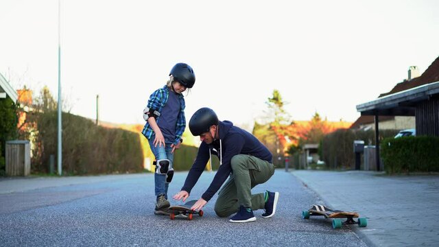 Father and son skateboarding on a suburban street.