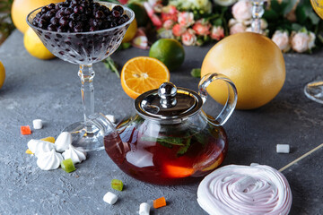 Fruit tea with mint, oranges and cranberries on a decorative background. Hot winter drinks. A teapot of hot tea