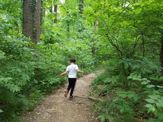 Naklejka na ściany i meble boy child walking on trail in woods or forest