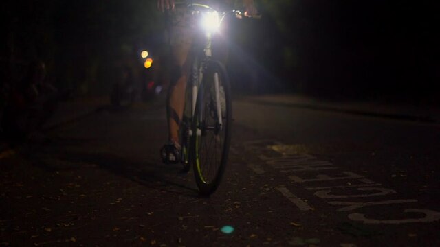 MS SLO MO Young woman cycling on street at night / London, England, UK