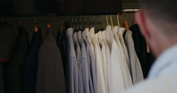 Close up of man choosing shirt and suit from his wardrobe.