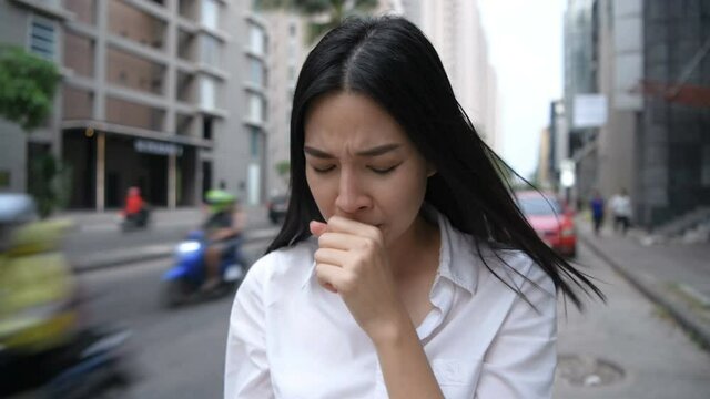 Travel concept. Asian woman coughing on the traffic background. 4k Resolution.