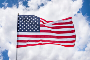 Obraz premium Close up of beautifully waving star and striped American flag; Concept for Memorial Day or 4th of July; White clouds background