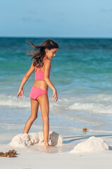 Niña en bikini rosa en playa azul del mar caribe durante vacaciones de verano