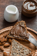 
Tasty breakfast. Sandwiches with chocolate and peanut butter and almonds on a wooden table.