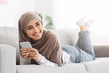 Online Flirting. Cheerful Arabic Girl Texting On Smartphone With Boyfriend