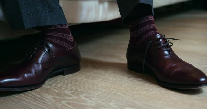 Close up of man tying laces of his brown leather shoes.