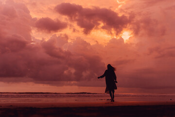 social distancing on the beach , pink and orange amazing cloudy sky , beautiful sunset , Bali Indonesia , solo outdoor walking 