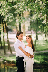 Newly-Wedded Couple Standing Embracing Outdoors In Nature Park, Vertical Shot