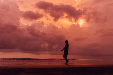 social distancing on the beach , pink and orange amazing cloudy sky , beautiful sunset , Bali Indonesia , solo outdoor walking 