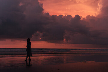 Fototapeta premium social distancing on the beach , pink and orange amazing cloudy sky , beautiful sunset , Bali Indonesia , solo outdoor walking 