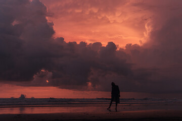 Obraz premium social distancing on the beach , pink and orange amazing cloudy sky , beautiful sunset , Bali Indonesia , solo outdoor walking 