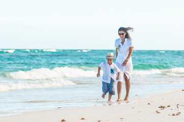 Mujer y niño con ropa de verano pasea juntos en playa del mar Caribe durante las vacaciones.