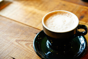 A cup of cappuccino coffee on wooden table top.