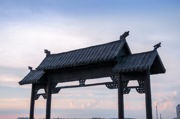 The roof of the gate in Chinese style against the background of the sunset sky
