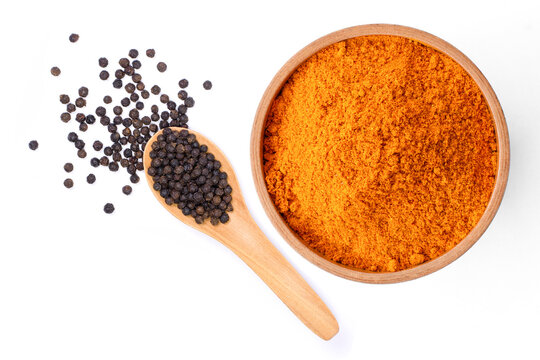 Curcumin powder ( tumeric ground, turmeric, Curcuma ) in wooden bowl and black pepper isolated on white background. Health benefits and antioxidant food concept. Top view.