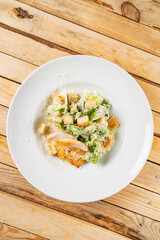 Fresh caesar salad in white plate, wooden background