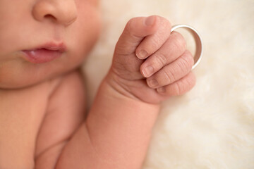 Newborn holding fathers wedding ring