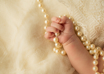 Newborn hand holding pearls