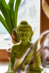buddha in springtime. The statue stands on a window surrounded by green plants.