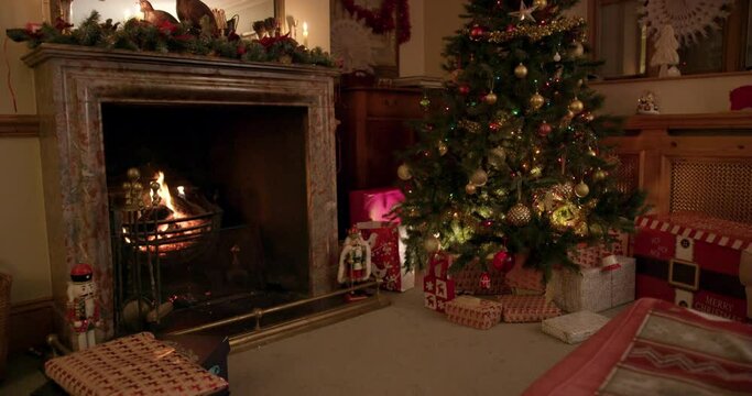 MS TU Christmas tree with gifts near fireplace in living room / Dinton, Wiltshire, UK