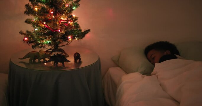 MS PAN Boy (6-7) sleeping in bed at Christmas tree / Dinton, Wiltshire, UK