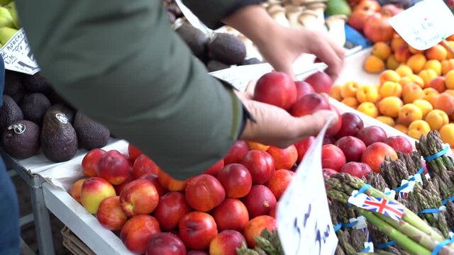 CU Vendor selecting nectarines in farmer's market / Norwich Market, Norfolk, United Kingdom