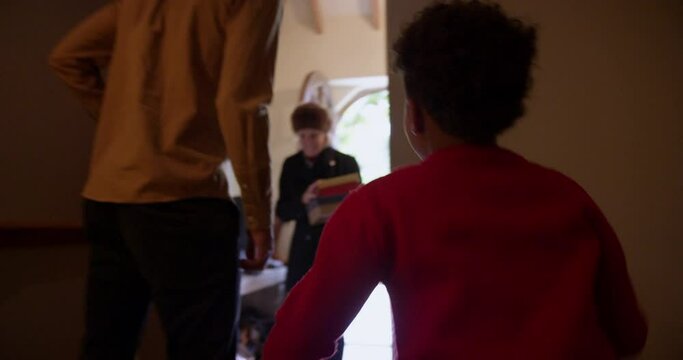 MS HANDHELD Boy (6-7) greeting grandmother entering house with Christmas gifts / Dinton, Wiltshire, UK